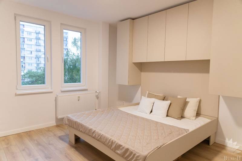 Bedroom in a 4-room apartment with a wooden decor floor and built-in wardrobes.