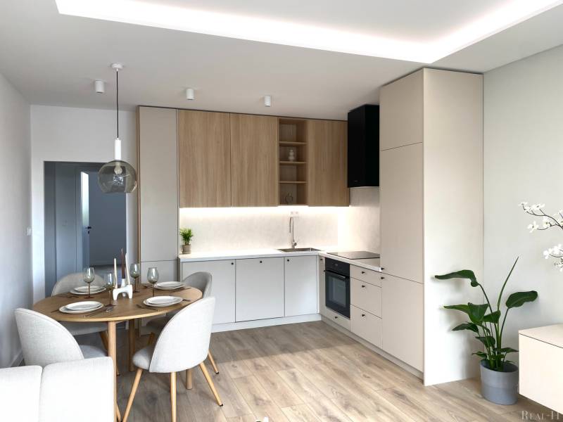Modern kitchen with a dining table, wood-patterned flooring, and white tiles.
