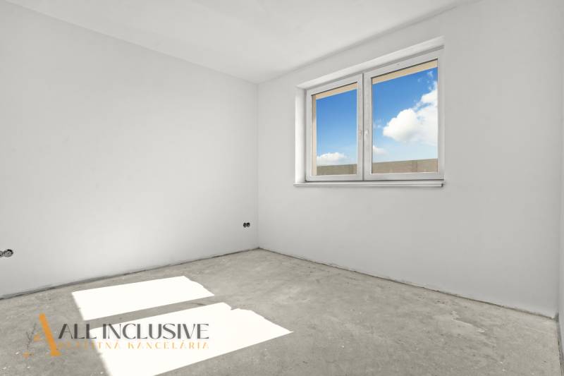 An empty room in a family house with white walls and a large window.