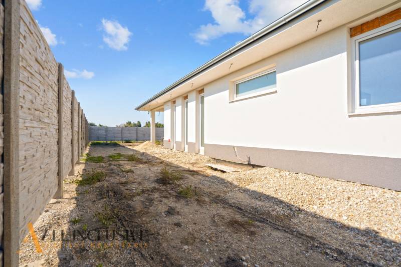 A family house in Gabčíkovo with a side view of the white facade and fencing.