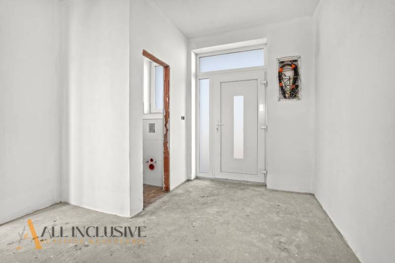 Entrance hallway in a family house with white walls and an incomplete floor.