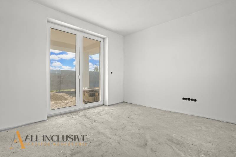 Empty room with large windows and a view of the exterior of a family house.