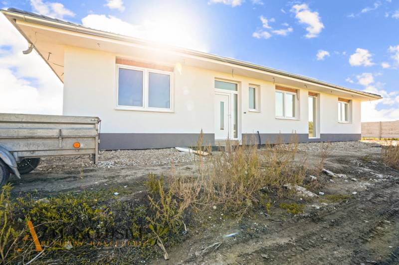 A family house in Gabčíkovo with a white facade and a trailer in front of the entrance.