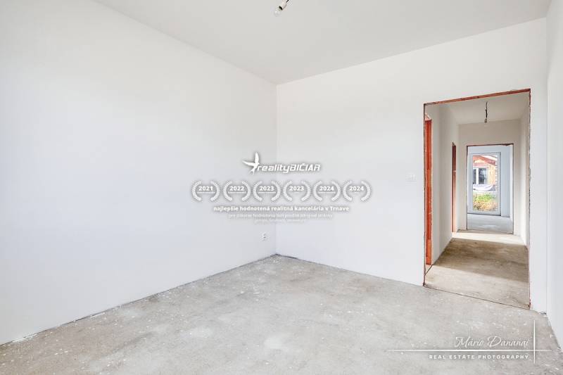 The interior of a family house with white walls and a hallway leading to another room.