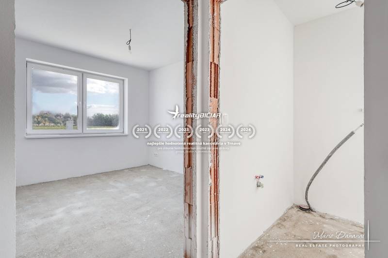 An empty room with a large window and unpainted walls in a family house.