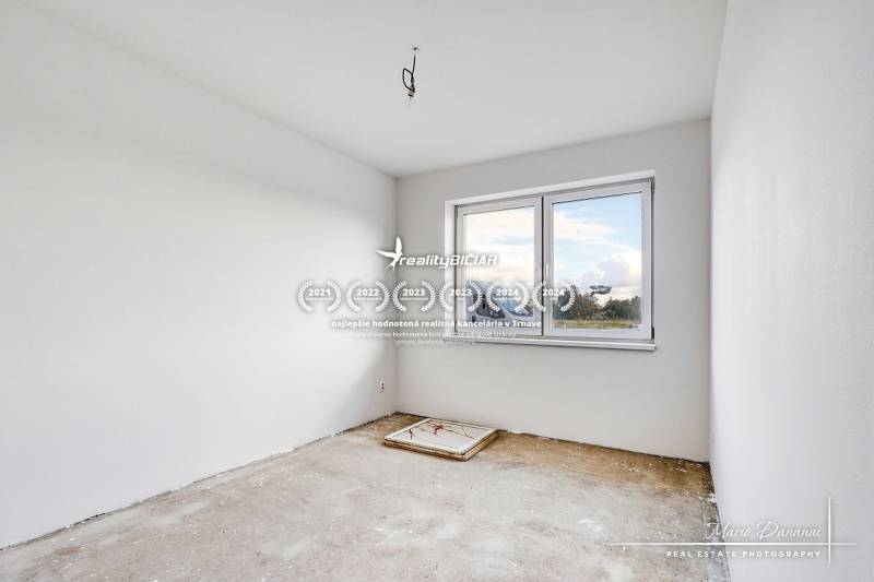 An empty room with white walls and a window, floor ready for finishing.