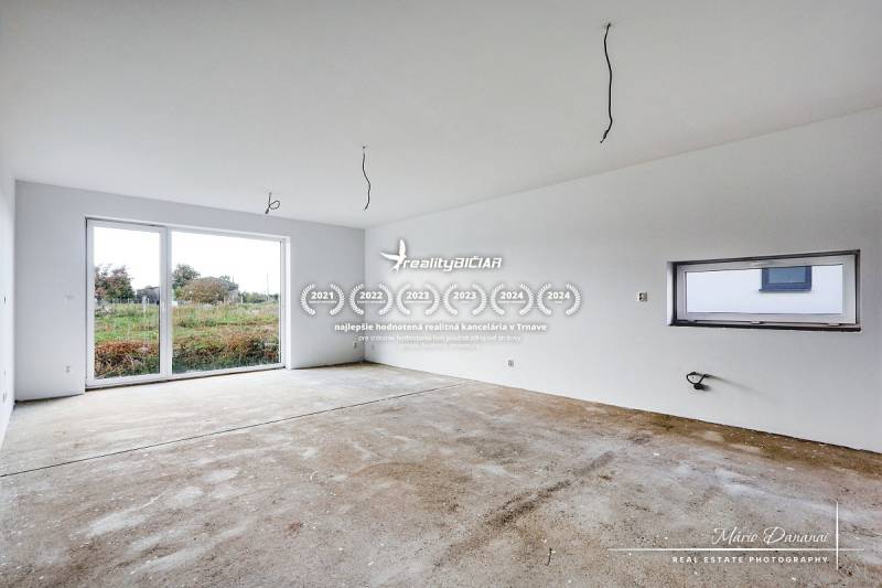 A spacious room in a family house with a large window and a concrete floor.
