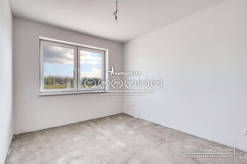 An empty room in a family house without flooring, with a large window and white walls.