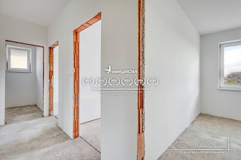 Interior of a family house with white walls and wooden door frames without flooring.