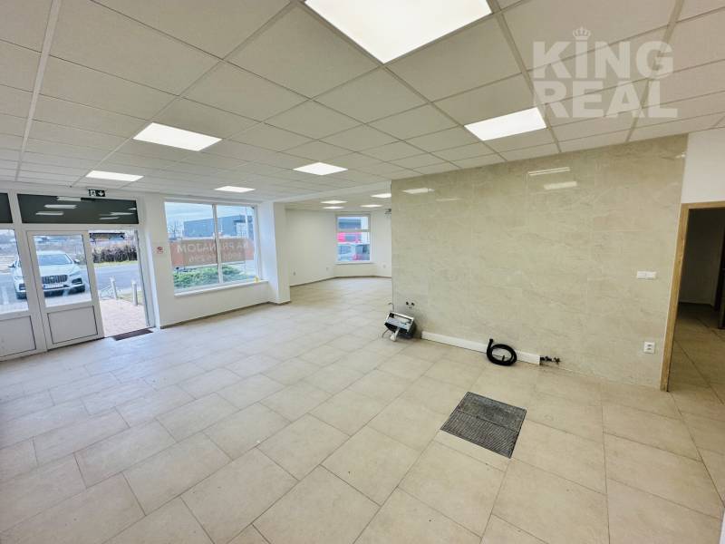 Interior of commercial spaces with large windows and light-colored tiles.