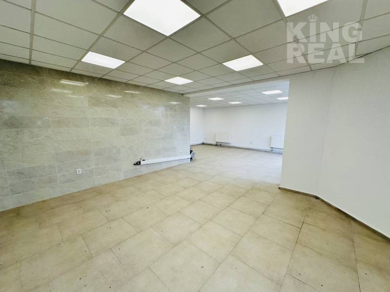 Spacious commercial spaces with tiles, white walls, and ceiling lights.