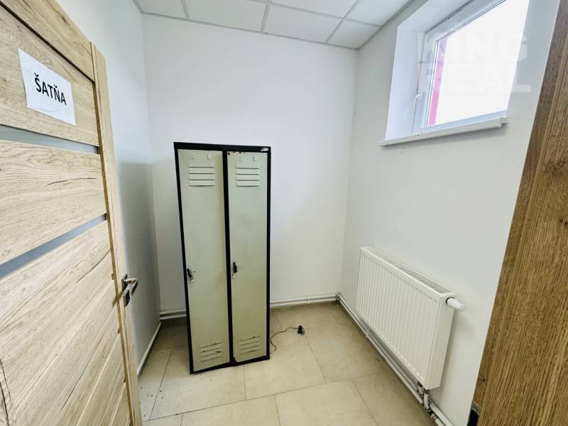 Changing room in commercial premises with storage lockers, white walls, and a radiator.