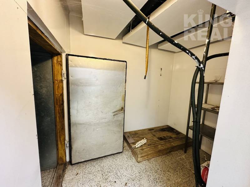 Cooling room in commercial premises with sturdy doors and metal shelves.