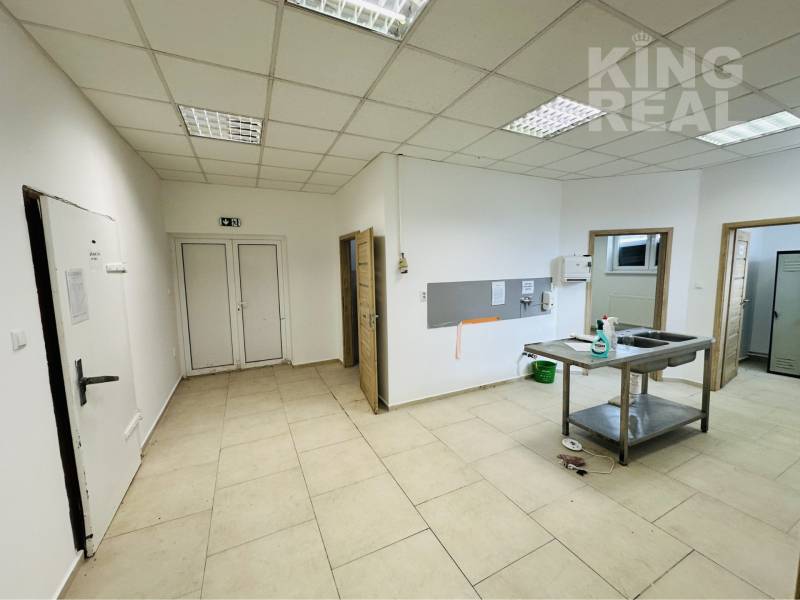 Commercial space with a sink and storage area with white walls and tiles.