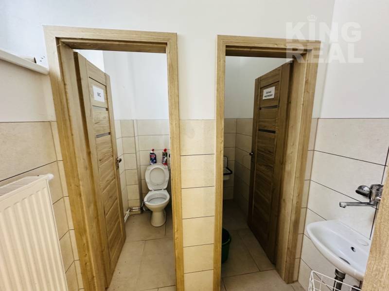 Interior of commercial premises with toilets and wooden doors.