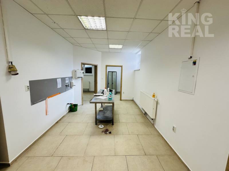 Commercial premises with tiles, white walls, and a table in the middle of the room.
