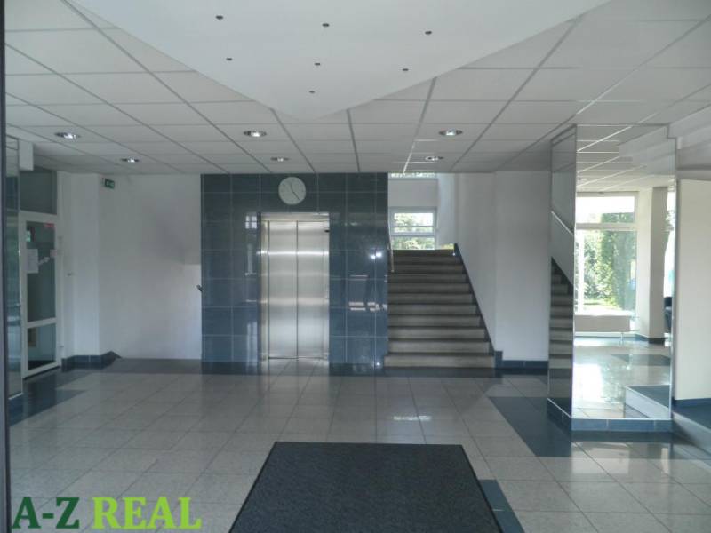 Offices with an elevator and staircase, mirrors reflecting light, tiled floor.