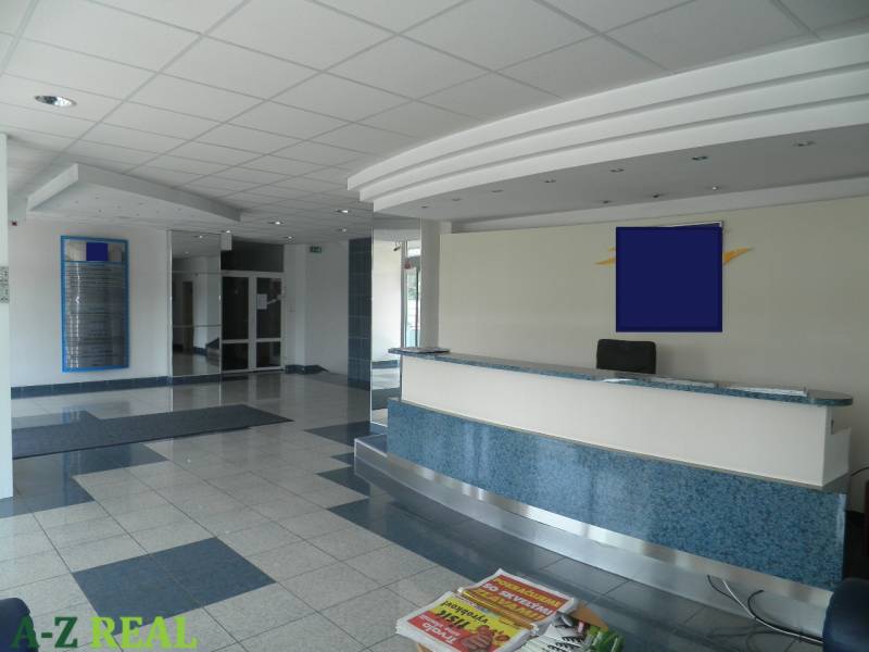 Reception in offices with tiles, ceiling panels, and magazines on the table.