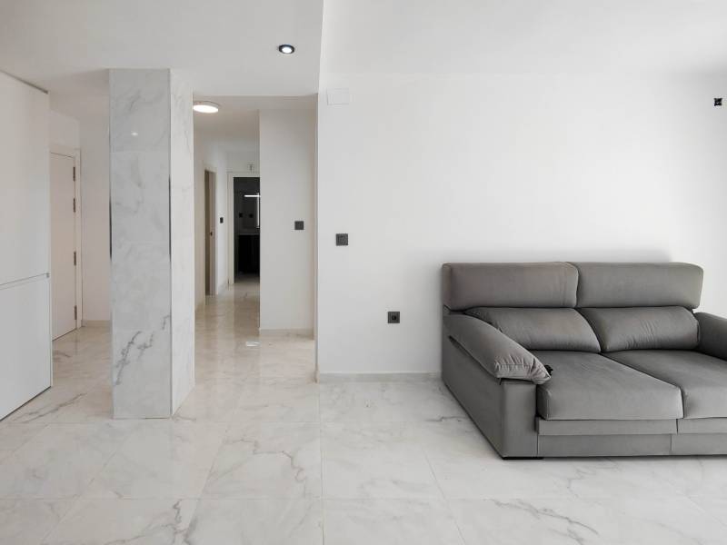 Interior of a 3-room apartment with a gray sofa and marble floor decor.