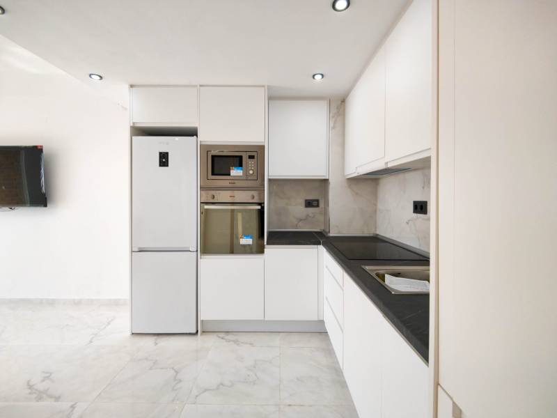 A kitchen in a 3-room apartment with a marble floor and modern appliances.