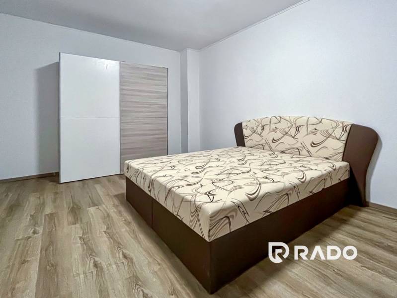 Bedroom in a 2-room apartment with a bed and a wardrobe, floor with wood decor.