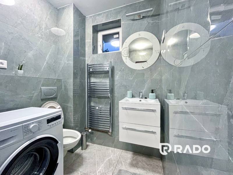 A bathroom with a washing machine and dark tiles in a 2-room apartment.