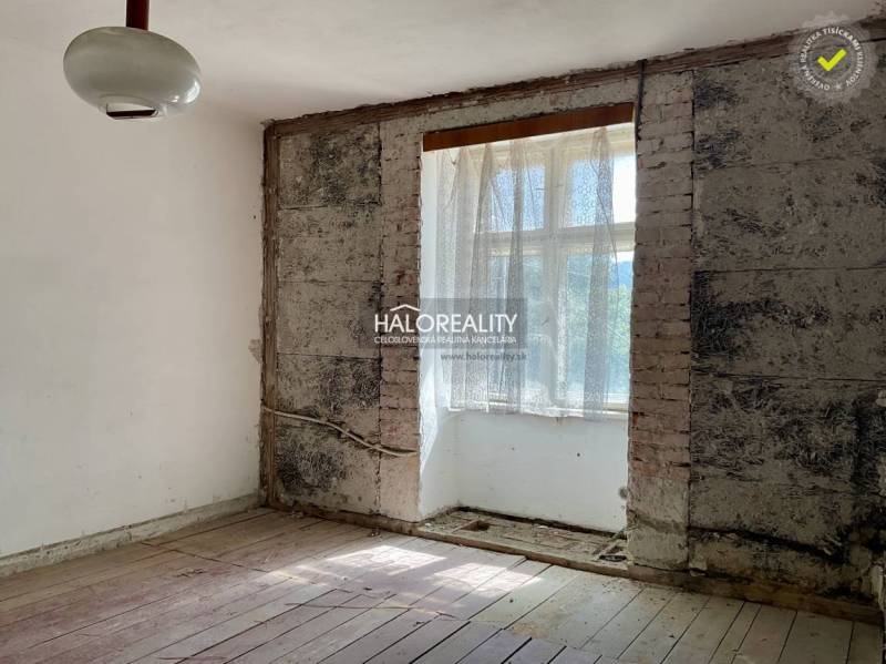A room with exposed brick and a wood-patterned floor in a family house.