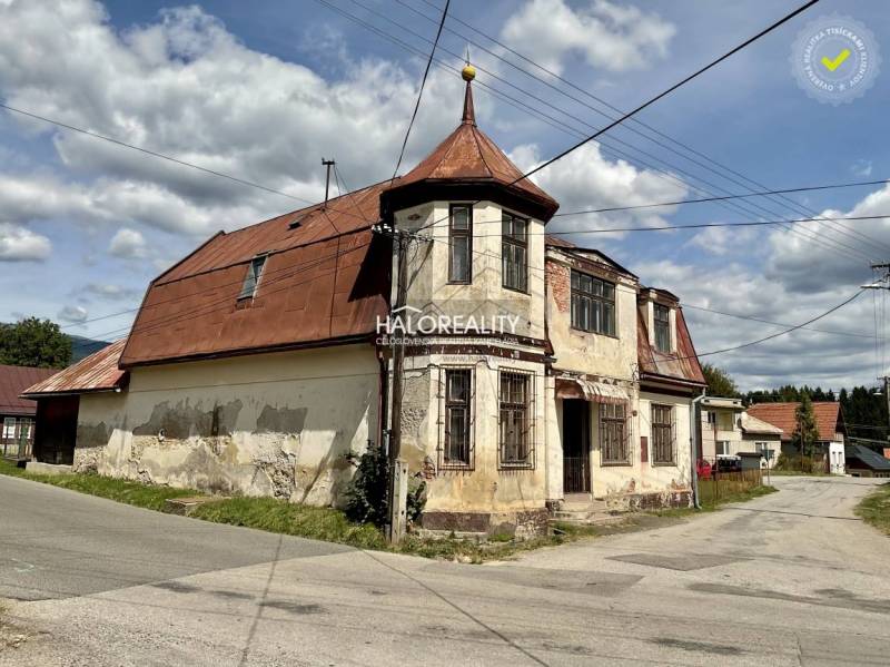 An older family house in Jasení, with a sloped metal roof on the corner of the street.