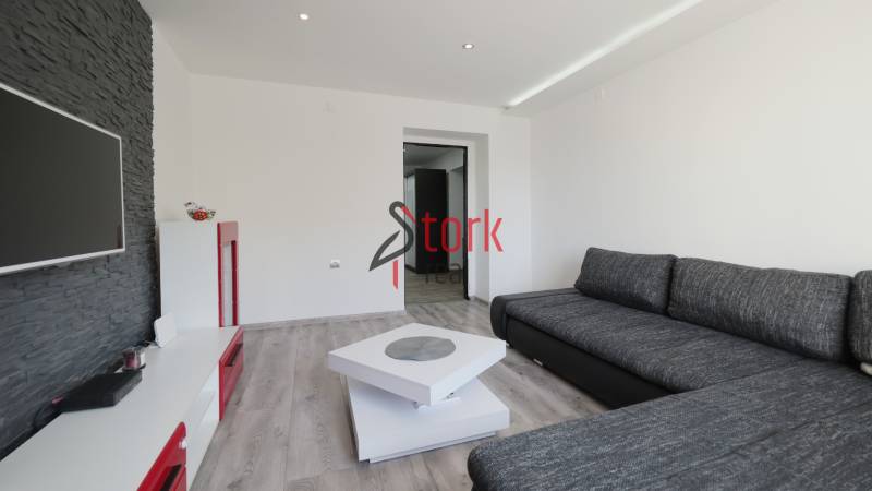 Living room with a corner sofa and television in a 2-room apartment, floor with wood decor.