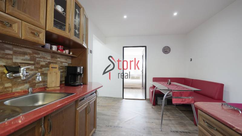 A kitchen in a 2-room apartment with dining, wooden cabinets, and a floor with a wooden decor.