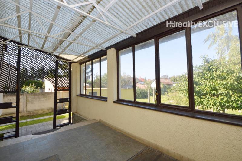 The veranda of a family house in Hegyeshalom with glazing and a view of the garden.