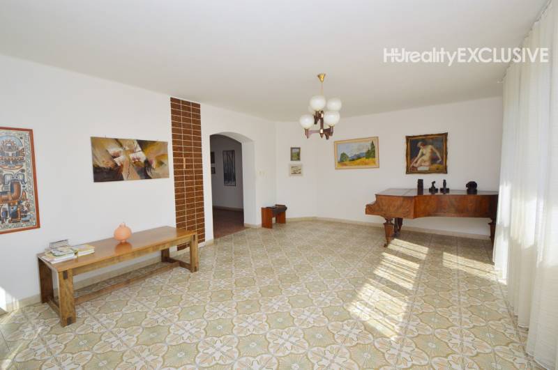 A bright living room in a family house with a grand piano and artistic paintings on the walls.