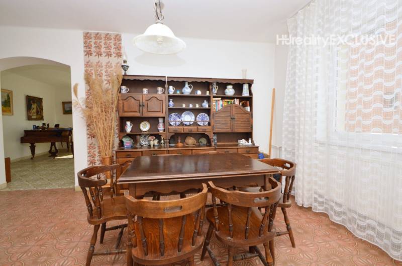 Dining area with wooden furniture and a patterned carpet in a family house.