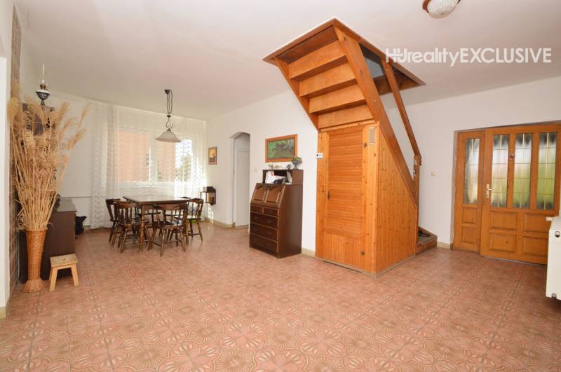 Dining room in a family house with wooden stairs, a large table, and a display cabinet.