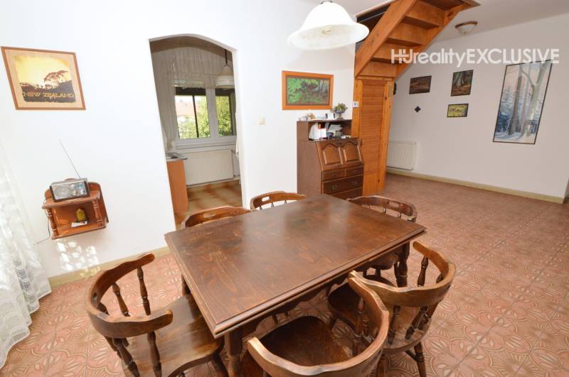 Dining room in a family house with wooden furniture and decor, entrance to the kitchen.
