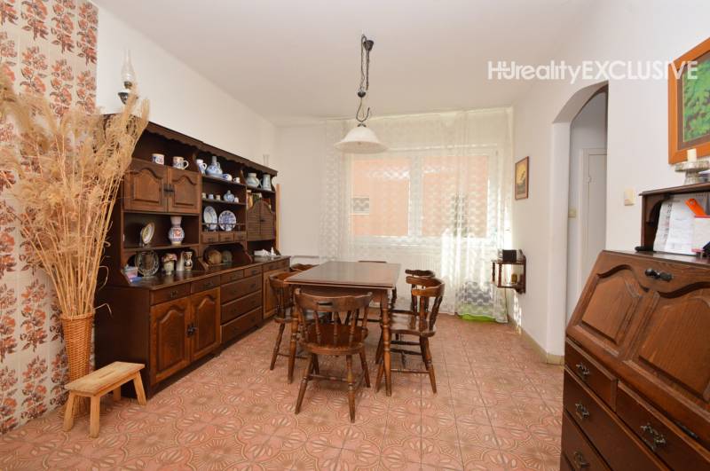 A dining room in a family house with floral wallpaper, wooden furniture, and ceramic accessories.