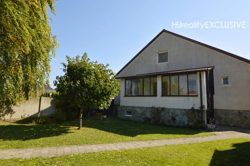 A family house in Hegyeshalom with a grassy garden, a walkway, and trees.