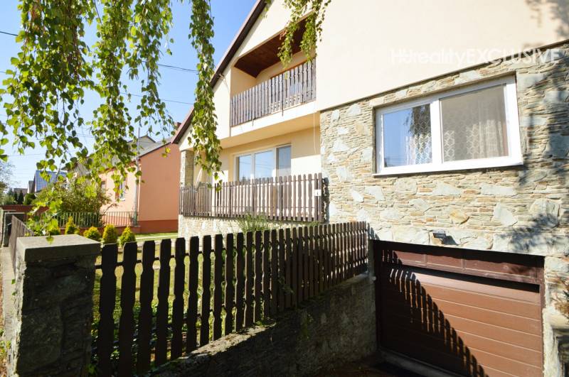 The exterior of a family house in Hegyeshalom with a stone facade and a wooden fence.
