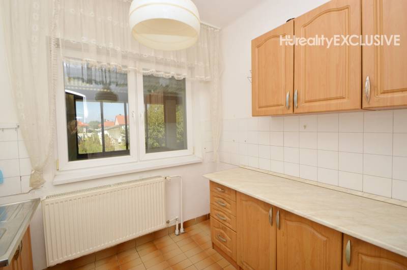 A kitchen in a family house with a simple kitchen unit and tiles.