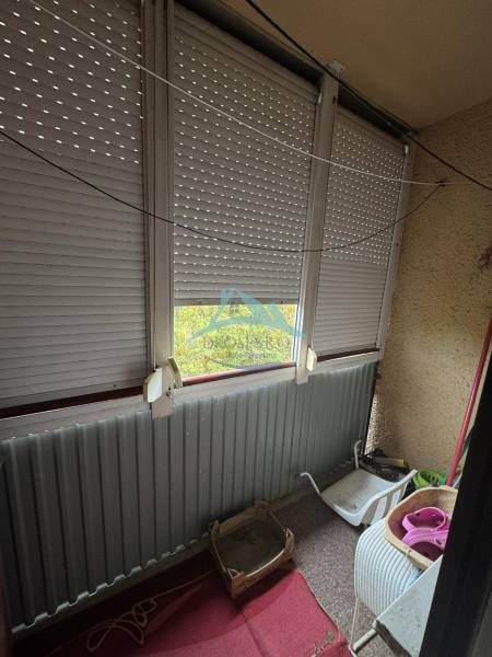 Glazed balcony in a 2-room apartment, with blinds and metal railing.