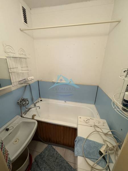 A small bathroom in a two-room apartment with a bathtub, sink, and washing machine.