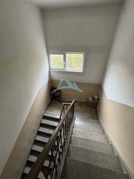A staircase with a wooden railing in a 2-room apartment, an interior space with a window.