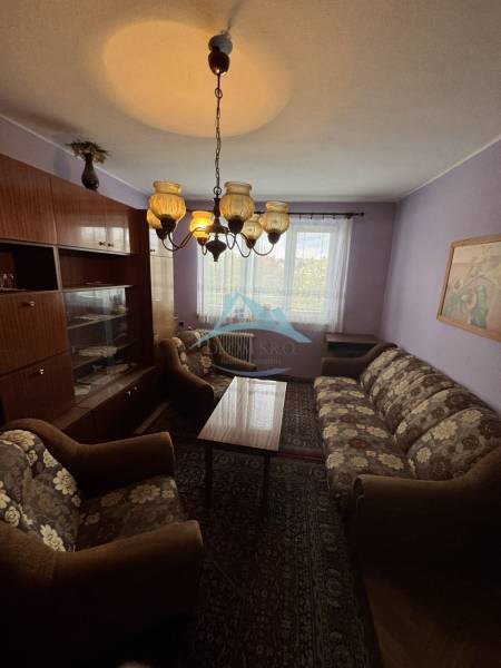 Living room in a two-room apartment with older furniture, a sofa, and a chandelier.
