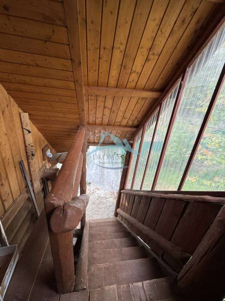 A staircase with wooden paneling in a cottage, overlooking the garden.