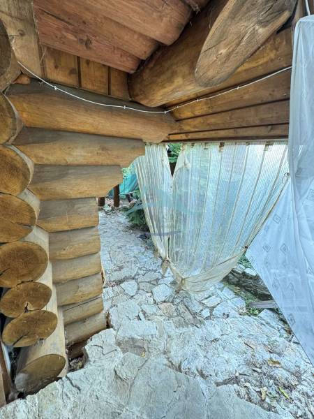 Wooden cottage in Dolné Rykynčice with a stone-paved area and curtains.