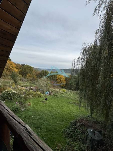 A garden with a lawn, trees, and a view of the hills from the Cottage in Dolné Rykynčice.
