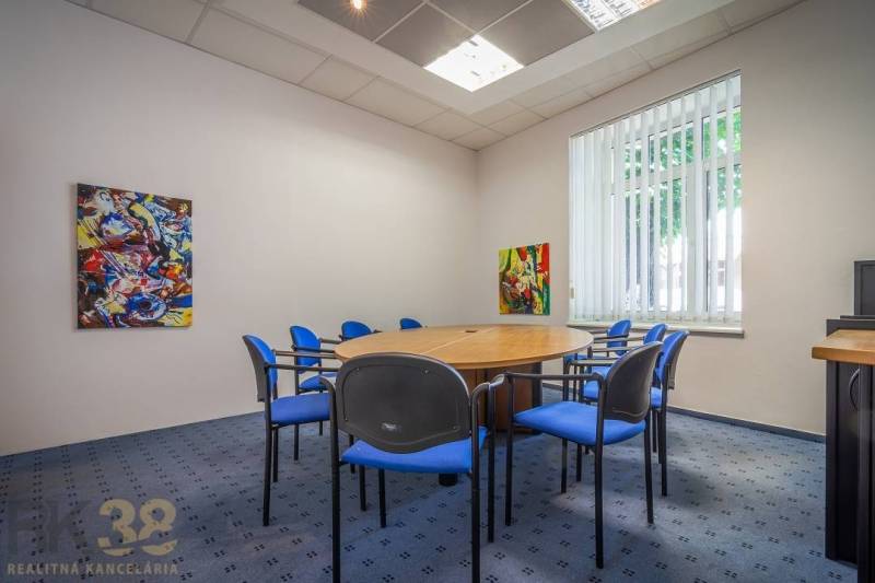 A kitchen in a building with a wooden decor floor and carpeted stairs.