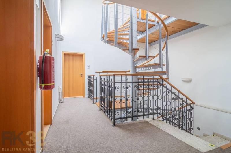 The interior of the building with wood-patterned flooring, white walls, and ceiling lights.
