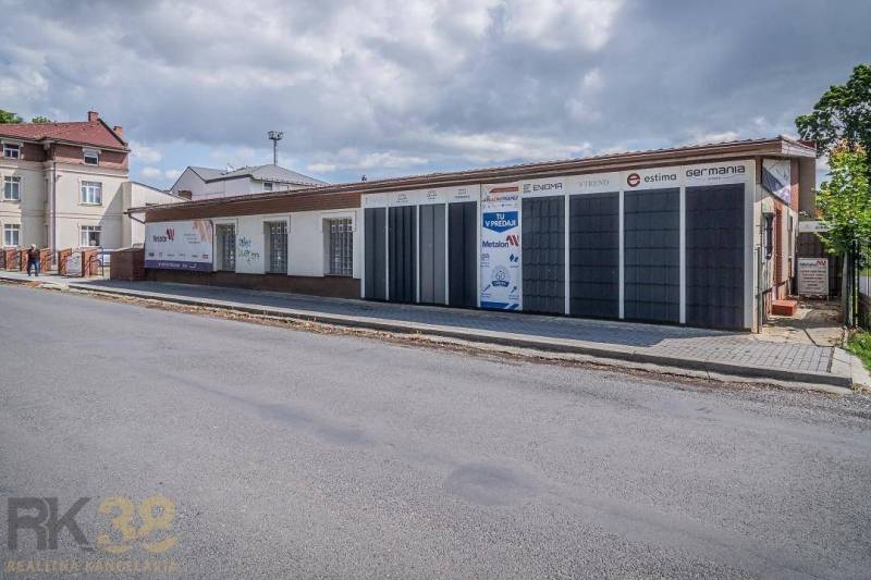 The building on Halatova Street in Poprad with a parking lot and trees in the background.
