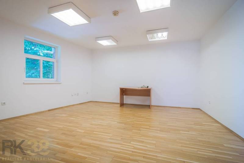A hallway with a kitchenette in a building with light walls and wooden cabinets.